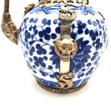 Blue and white ceramic teapot with silver decorative elements on a white background
