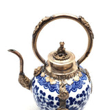 Blue and white ceramic teapot with silver accents on a white background