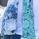 A woman accessorized with a two-sided silk scarf featuring blue and white patterns.