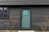 A handcrafted sailor's wreath made of rope, with colors resembling sand, sea, and sky, displayed on a door.