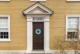 A handcrafted sailor's wreath made of rope, with colors resembling sand, sea, and sky, displayed on a door.