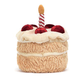 A plush toy in the shape of a birthday cake with two layers, decorated with a red and white striped candle on top.