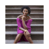 Photograph of a black woman wearing a pink dress sitting on steps.