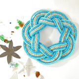 A handcrafted sailor's wreath made of rope, with colors resembling sand, sea, and sky.