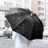 Person holding a black umbrella in a snowy city street
