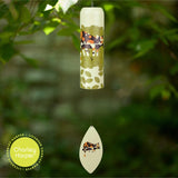 Decorative wind chime with Charley Harper design against a green leafy background