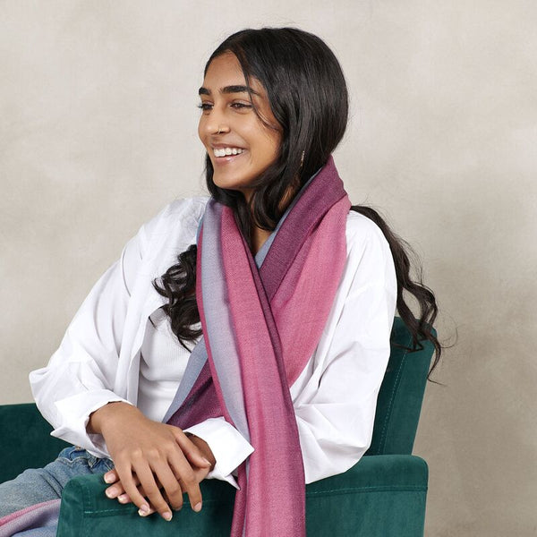 Woman wearing a pink scarf sitting on a green chair against a beige background