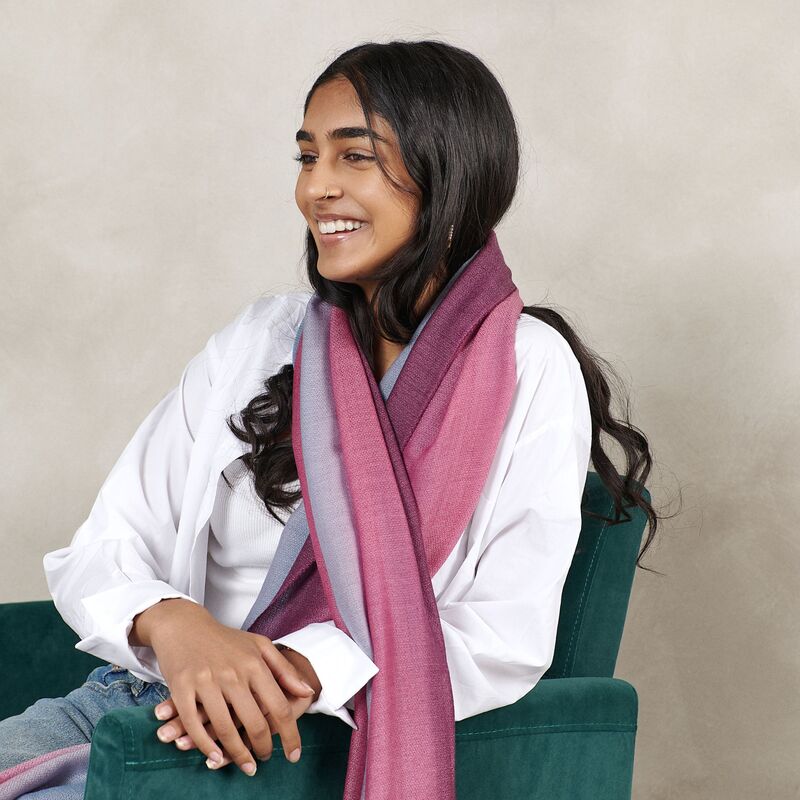 Woman wearing a pink scarf sitting on a green chair against a beige background