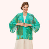 Woman wearing a teal floral kimono-style jacket on a white background