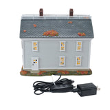 Model house with autumn decorations and power adapter on a white background