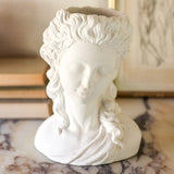 White cement bust on a marble surface with a blurred background