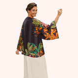 Woman wearing a black floral blouse with colorful patterns on a white background