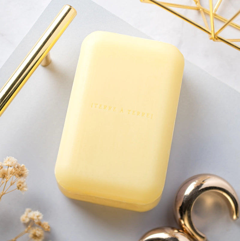 Yellow bar of soap on a light gray surface with gold accents.
