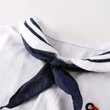 Close-up of a white romper with a navy blue tie on a light gray background