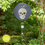 Decorative suncatcher with skull design hanging in a garden