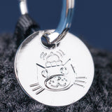 Silver cat-shaped pendant on a dark fabric background
