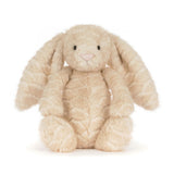 A plush stuffed bunny toy in a light cream-beige color with long floppy ears, black bead eyes, and a small pink stitched nose, photographed on a clean white background.