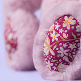 Close-up of pink bunny feet with floral pattern on a light background