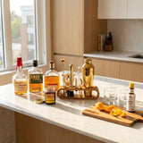 Alcohol bottles and bar tools on a kitchen counter with a window view.