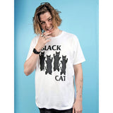 A model wearing a white graphic t-shirt with a black print of four cats and the text 'BLACK CAT' against a solid blue background.