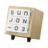 A modern wooden calendar block clock with white tiles displaying the date January 3rd, featuring a light oak wood frame and small black feet on a white background.