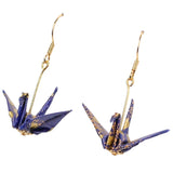 A pair of dangling origami crane earrings with gold-tone hooks and blue-and-gold paper cranes on a plain white background.