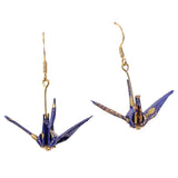 A pair of dangling origami crane earrings in deep blue with gold accents and gold-tone hooks, shown against a plain white background.