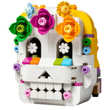 A LEGO building set skull decorated with colorful flower crowns and gears, shown on a plain white background.