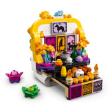 A colorful toy building-block set styled like a Day of the Dead altar or altar stand, with decorative panels, flowers, candles, drinks, and small accessories, shown on a plain white background.