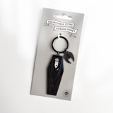 A black coffin-shaped keychain with a small bat charm, attached to a gray retail card labeled 'Collectable Cities x Edward Gorey'.