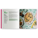An open cookbook spread showing a recipe page on the left with text and ingredients for 'Rice Vermicelli with Vegetables,' and a food photograph on the right of prepared rice vermicelli on a patterned plate over a green marble-style surface.