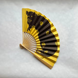 Handheld fan with black boar design on yellow background