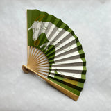 Handheld fan with green and brown striped design featuring a goat on a light gray background