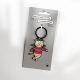 An enamel pin of the character Edward Gorey's cat wearing a red and blue striped sweater, attached to a black split ring and mounted on a grey cardboard display card. The card features 'Collectable Cities x Edward Gorey' branding.