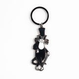 A black and white cartoon cat keychain charm wearing a top hat and cane, attached to a black split key ring on a plain white background.