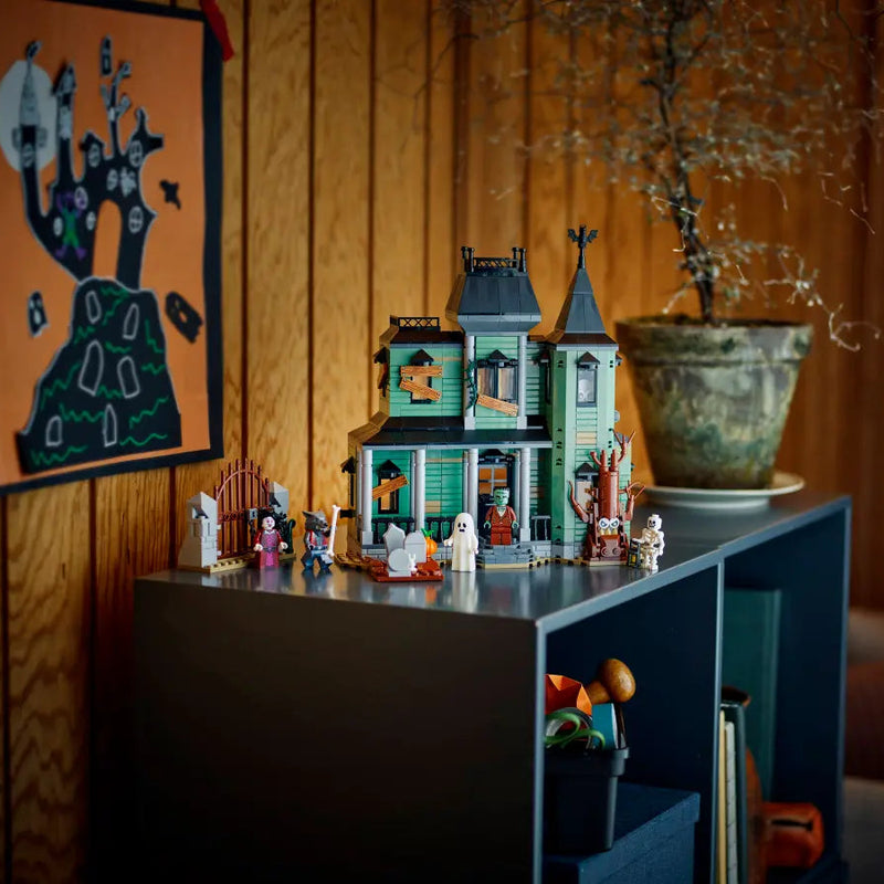 Toy house set on a shelf with decorative items against a warm-toned wall.