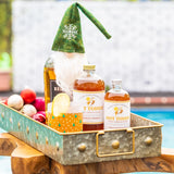 Hot toddy bottles with a decorative gnome and ornaments in a metal tray by a pool.