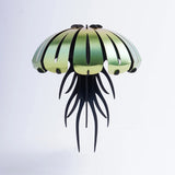 Decorative jellyfish-shaped object with green top and black bottom on a light gray background