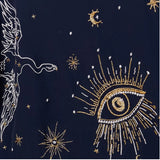 Close-up of a navy blue fabric featuring intricate gold and white embroidery of celestial motifs, including a large eye with radiating rays, stars, and a crescent moon.