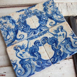 Set of ceramic tiles with blue mermaid design on a wooden surface