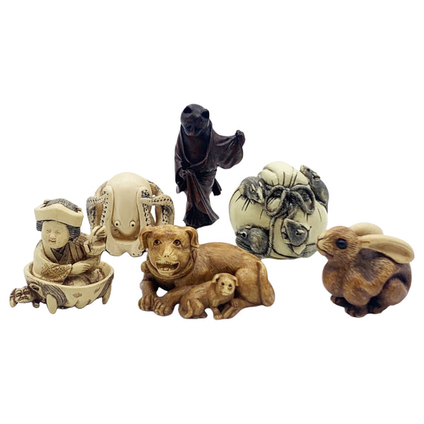A collection of various netsuke, or Japanese toggle figurines, featuring different animal and human figures, made of beige and black materials.