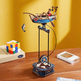 Toy fisherman with a small boat and fishing reel on a stand against a yellow wall