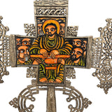 Decorative cross with intricate designs and colorful central figure on a white background