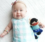 Baby holding a knitted doll on a white background