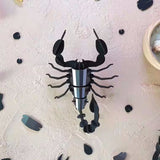 Black scorpion-shaped object on a textured white surface