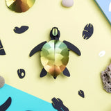 3D paper turtle model on a yellow background with decorative elements