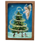 Boxed notecards featuring a whimsical Christmas scene with a glowing green tree, a white faerie figure, and three rabbits on a snowy ground, all set against a dark blue night sky. 