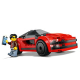LEGO model of a red sports car with a figure holding a phone on a white background