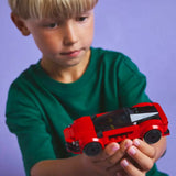 Child holding a red toy car against a purple background