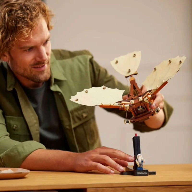 Man holding a detailed model of a mechanical device on a wooden table.